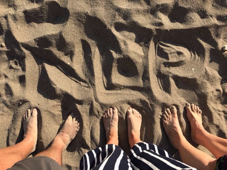 Three pairs of bare feet standing in the sand, symbolizing grounding and connection, a visual metaphor for the principles discussed in the NLP blog